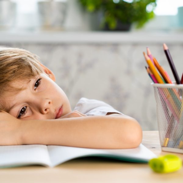 A tired schoolboy sleeps at the table, back to school, children's stress from studying, psychology.